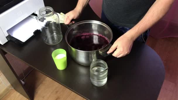 Человек наливает в стеклянную банку выжатый виноградный сок. Делать домашнее вино во время эпидемии. Вид сбоку. — стоковое видео
