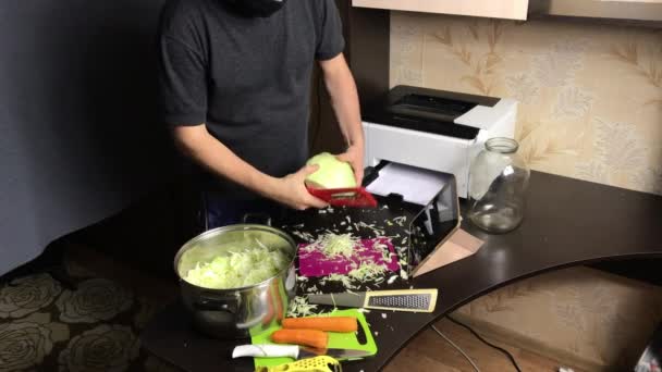 A man in a medical mask chops a cabbage. Broadcasts the process and quality of grinding via video link. Sauerkraut at home during a pandemic. — Stock Video