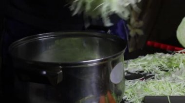 Adam parçalanmış lahanayı bir tencereye koyar ve elleriyle ezmeye başlar. Salgın sırasında evde lahana turşusu vardı. Yakın çekim..