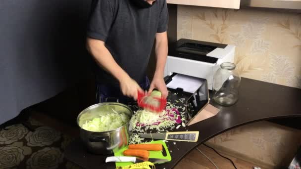 A man in a medical mask chops a cabbage. Broadcasts the process and quality of grinding via video link. Sauerkraut at home during a pandemic — Stock Video