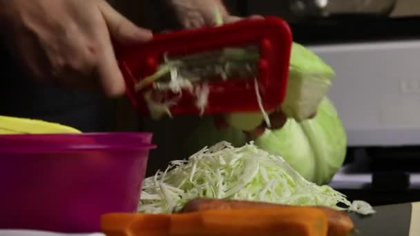 A man shreds cabbage. There are carrots nearby. Sauerkraut at home during a pandemic. Close-up shot. — Stock Footage A man shreds cabbage. There are carrots nearby. Sauerkraut at home during a pandemic. Close-up shot. Stock Video
