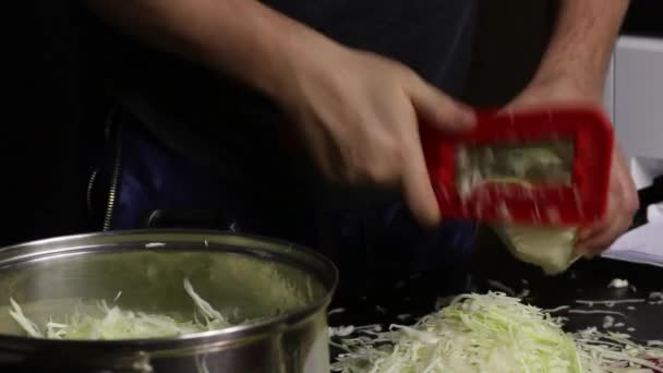 Der Mann zerkleinert den Kohl und legt ihn in den Topf. Überträgt den Prozess per Videolink. Sauerkraut zu Hause während einer Pandemie. Nahaufnahme. — Stockvideo