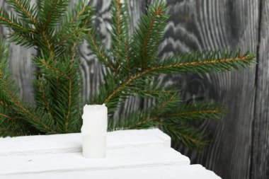 Beyaz çam tahtalarında mum. Köknar dallarının arka planına karşı.