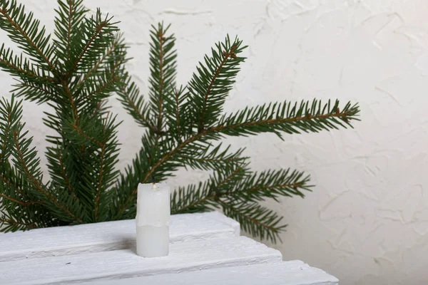 Candle on white pine boards. Against the background of fir branches.