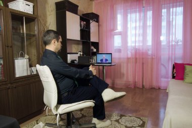 Adamın biri dizüstü bilgisayardan video konferansı izliyor. Kendini izole edilmiş bir dairede..