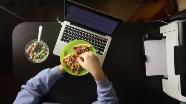 De man is aan het dineren in de laptop. Pizza en salade eten. van bovenaf gefilmd. — Stockvideo