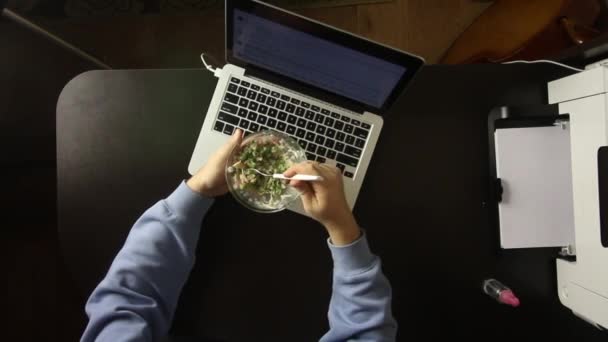 Der Mann sitzt beim Abendessen am Laptop. Salat essen. Von oben gefilmt — Stockvideo