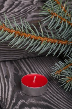 Çam ağacının üzerinde mavi ladin dalları. Yakınlarda kırmızı bir mum var. Yakın çekim..