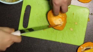 Adamın biri portakal kabağını parçalara ayırıyor. Yukarıdan yakın çekim.