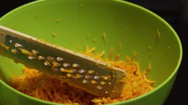 Adam bir rende alır ve üzerine balkabağı parçaları sürer. Yan taraftan yakın çekim..