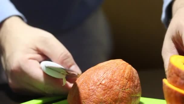 Ein Mann schneidet mit einem Messer einen kleinen orangefarbenen Kürbis. Nahaufnahme — Stockvideo