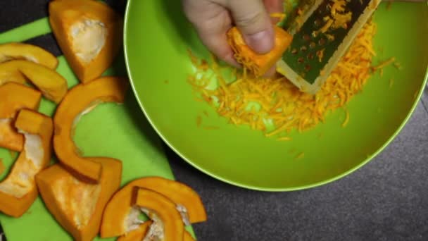 Un homme râpe des tranches de citrouille orange. Gros plan d'en haut.. — Video