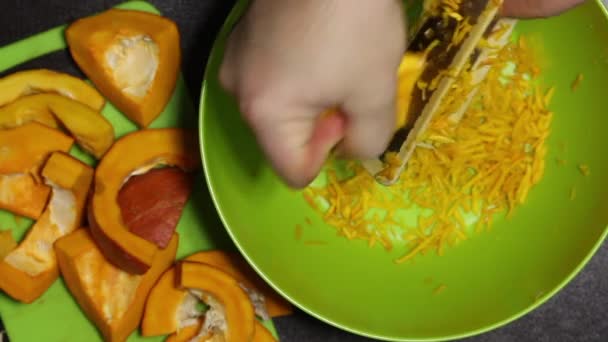 Um homem rala fatias de abóbora laranja. Close-up tiro de cima — Vídeo de Stock