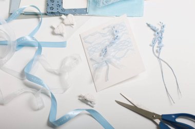 Tebrik kartları hazırlıyorum. Masanın beyaz yüzeyinde el işi aksesuarlar. Kurumuş çiçekler ve el işleri için kurdeleler. Yaratıcılık için araçlar.