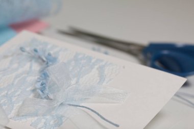 Tebrik kartları hazırlıyorum. Masanın beyaz yüzeyinde el işi aksesuarlar. Kurumuş çiçekler ve el işleri için kurdeleler. Yaratıcılık için araçlar.