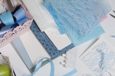 Tebrik kartları hazırlıyorum. Masanın beyaz yüzeyinde el işi aksesuarlar. Kurumuş çiçekler ve el işleri için kurdeleler. Yaratıcılık için araçlar.