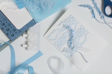 Tebrik kartları hazırlıyorum. Masanın beyaz yüzeyinde el işi aksesuarlar. Kurumuş çiçekler ve el işleri için kurdeleler. Yaratıcılık için araçlar.