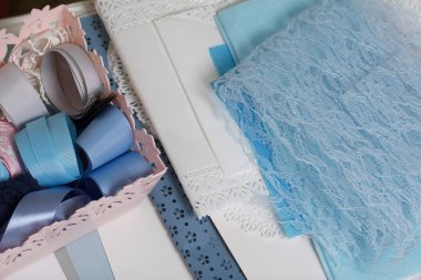 Tebrik kartları hazırlıyorum. Masanın beyaz yüzeyinde el işi aksesuarlar. Kurumuş çiçekler ve el işleri için kurdeleler. Yaratıcılık için araçlar.