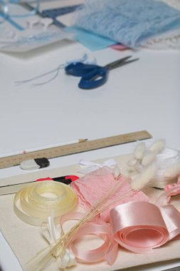 Tebrik kartları hazırlıyorum. Masanın beyaz yüzeyinde el işi aksesuarlar. Kurumuş çiçekler ve el işleri için kurdeleler. Yaratıcılık için araçlar.