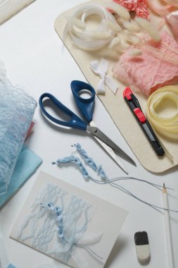 Tebrik kartları hazırlıyorum. Masanın beyaz yüzeyinde el işi aksesuarlar. Kurumuş çiçekler ve el işleri için kurdeleler. Yaratıcılık için araçlar.