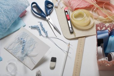 Tebrik kartları hazırlıyorum. Masanın beyaz yüzeyinde el işi aksesuarlar. Kurumuş çiçekler ve el işleri için kurdeleler. Yaratıcılık için araçlar.