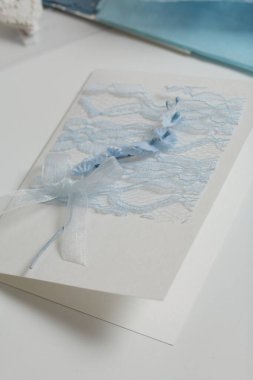 Tebrik kartları hazırlıyorum. Masanın beyaz yüzeyinde el işi aksesuarlar. Kurumuş çiçekler ve el işleri için kurdeleler. Yaratıcılık için araçlar.