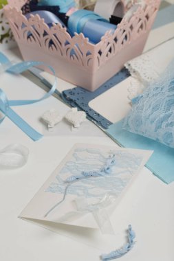 Tebrik kartları hazırlıyorum. Masanın beyaz yüzeyinde el işi aksesuarlar. Kurumuş çiçekler ve el işleri için kurdeleler. Yaratıcılık için araçlar.