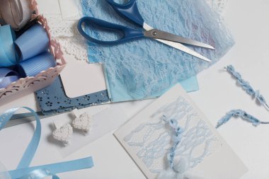 Tebrik kartları hazırlıyorum. Masanın beyaz yüzeyinde el işi aksesuarlar. Kurumuş çiçekler ve el işleri için kurdeleler. Yaratıcılık için araçlar.