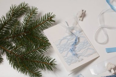 Tebrik kartları hazırlıyorum. Beyaz bir masa yüzeyinde el işi aksesuarlar ve köknar dalları. Kurumuş çiçekler ve el işleri için kurdeleler. Yaratıcılık için araçlar.