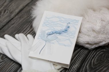 Kış örülmüş kürk ve eldivenli şapka. - Beyaz. Tebrik kartının yanında. Siyah çam ağaçlarının üzerinde yatıyorlar..