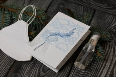 Tebrik kartı, tıbbi maske ve antiseptik. Siyah çam ağaçlarının üzerinde yatıyorlar..