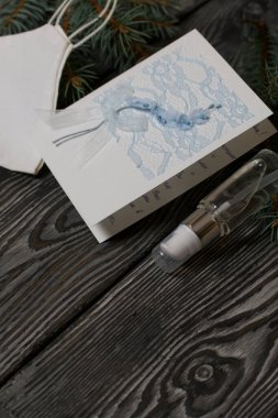 Tebrik kartı, tıbbi maske ve antiseptik. Siyah çam ağaçlarının üzerinde yatıyorlar..