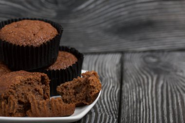 Yulaflı çikolatalı kek. Gümüş bir tepside hazır. Biri kesiği göstermek için kırılmış. Siyah çam tahtalarında.