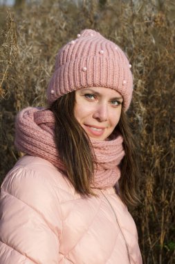 Kurumuş uzun otların arasında sonbahar kıyafetleri içinde bir kız. Parkta doğa yürüyüşü..