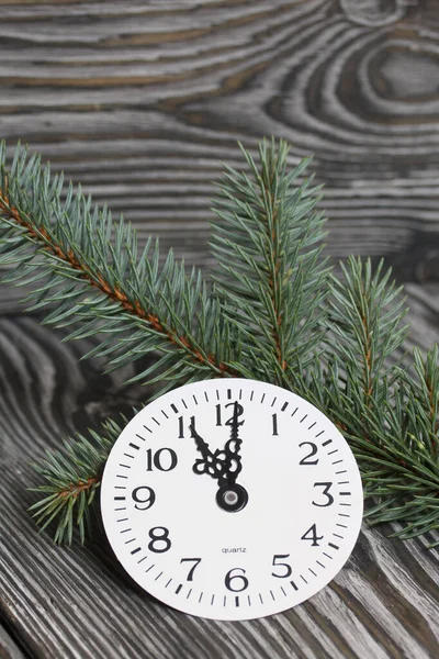 Clock dial and fir branches. On black pine boards.
