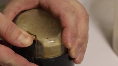 Bir adam kahve öğütücüsü kullanarak yulaf ezmesini una çeviriyor. Kaliteyi kontrol ediyor. Yakın çekim.