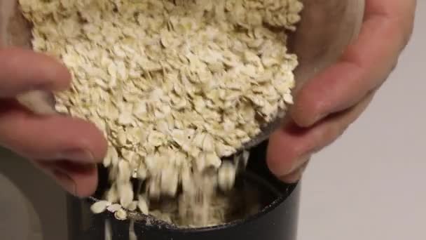 Um homem está a deitar farinha de aveia num moedor de café. Moagem-los em farinha. Imagem de close-up. — Vídeo de Stock