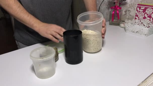Um homem transforma farinha de aveia em farinha. Usando um moedor de café. — Vídeo de Stock
