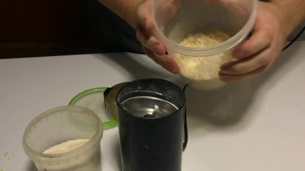 A man is pouring oatmeal into a coffee grinder. Grinds them into flour. — Stock Video