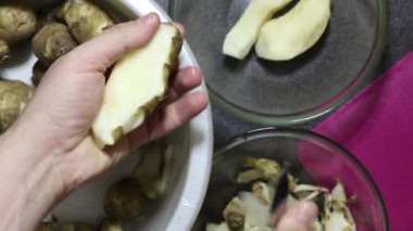 Bir adam mutfak bıçağıyla Kudüs enginarını soyuyor. Kabuğu bir kabuğa, soyulmuş sebzeyi başka bir kabuğa atar. Yukarıdan yakın çekim