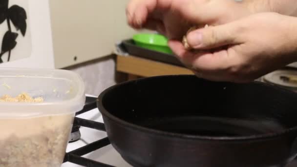 Der Mann brät Schnitzel. Er nimmt Hackfleisch aus dem Behälter und rollt die Bällchen. Sie gibt sie in eine heiße Pfanne. Nahaufnahme. — Stockvideo