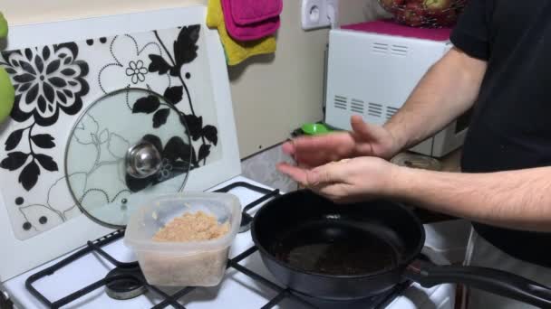 O homem prepara costeletas. rola bolas de carne picadas e coloca-os em uma panela de ato de fritar quente. Nas proximidades é um recipiente com carne picada. — Vídeo de Stock