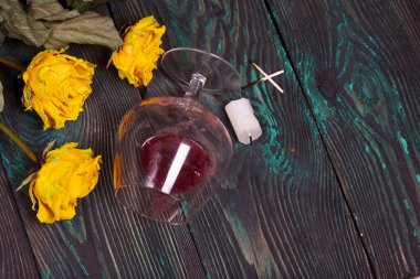 Bir buket kurutulmuş sarı gül ve mum koçanı. Devrilmiş bir bardak ekşi şarap. Çam ağacında.