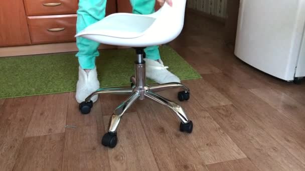 Bir kadın koltuğu bir bilgisayar sandalyesinin kaldırma mekanizmasına yerleştirir. Kurulumdan sonra kontrol eder. — Stok video