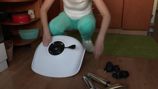 그 여자는 바퀴달린 컴퓨터 의자를 수집 한다. 사무실 의자의 일부는 아파트 바닥에 있다. 근접 촬영. — 비디오