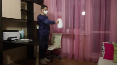 Tıbbi maskeli bir adam kendini izole ederek jimnastik yapar. Dambıl yerine konserve deterjan. Önünüzdeki dambılları sırayla kaldırın..