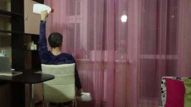 Tıbbi maskeli bir adam kendini izole ederek jimnastik yapar. Dambıl yerine konserve deterjan. Otururken dambılları yukarı kaldırır. Arkadan çekilmiş..