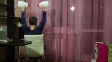 Tıbbi maskeli bir adam kendini izole ederek jimnastik yapar. Dambıl yerine konserve deterjan. Oturmuş halterli pres. Arkadan çekilmiş..