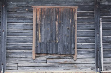 Eski ahşap kayalık ev. Kütükler zamanla kararır. Pencere tahtalarla kapatılmış..