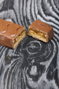 Doğranmış çikolata. Karamel ve fındık dolu. Siyah çam tahtalarında.